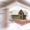 Hand holding house in front of blurred background