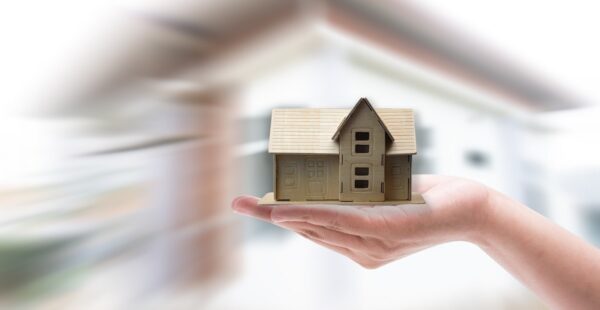 Hand holding house in front of blurred background