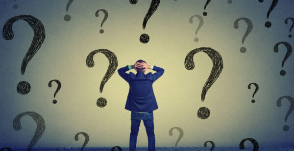 Man holds head amid question marks