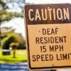 Caution deaf resident 15mph speed limit sign in quiet street