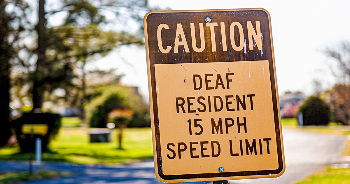 Caution deaf resident 15mph speed limit sign in quiet street