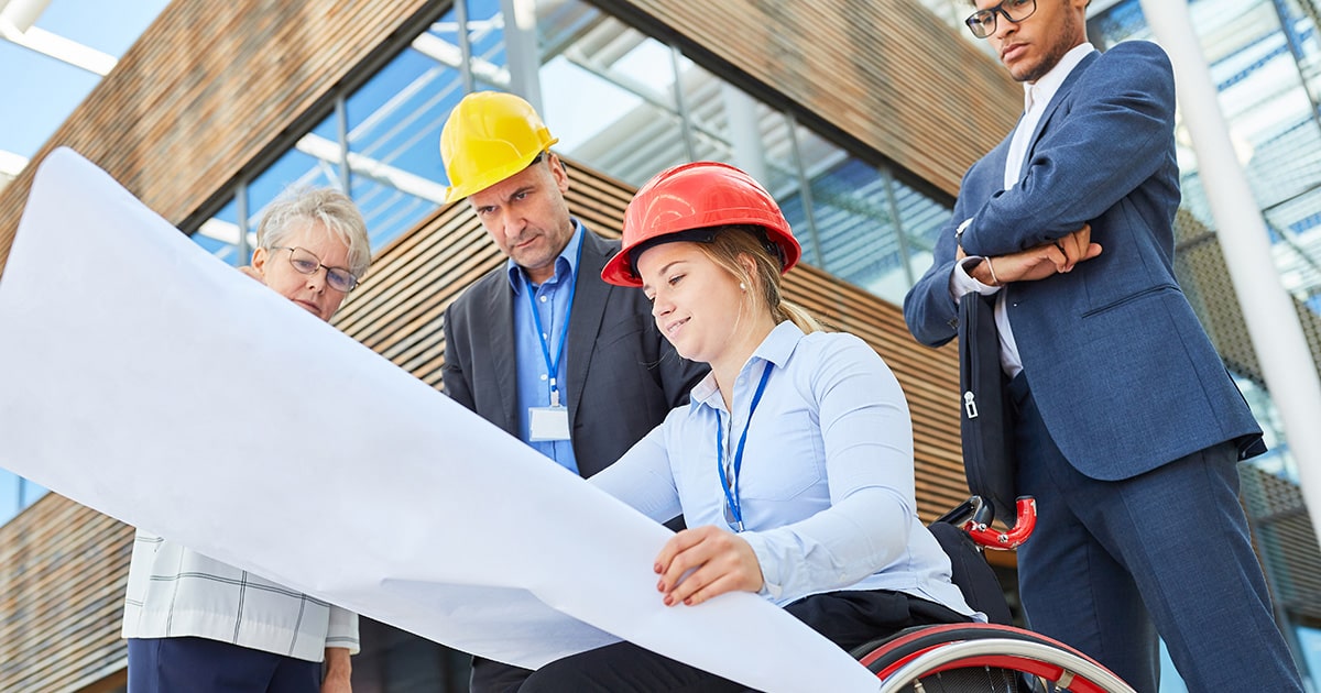 Worker in wheelchair on worksite with hardhat