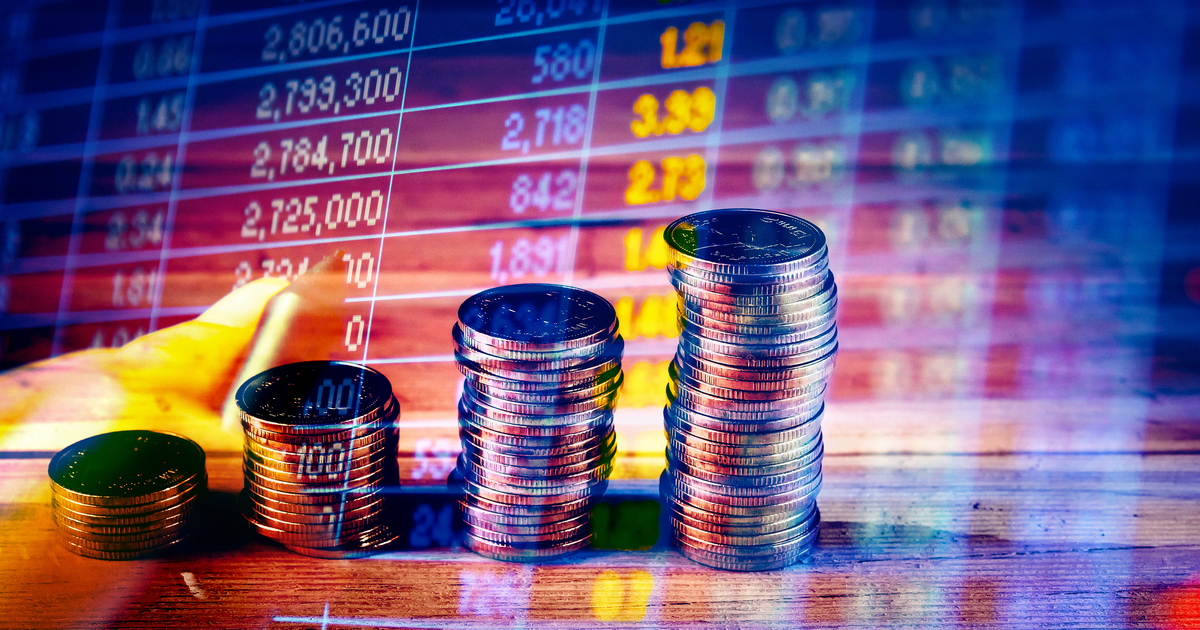 Stacks of coins in front of sharemarket board