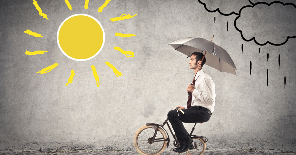 Businessman riding a bike with an umbrella in sunny and rainy weather