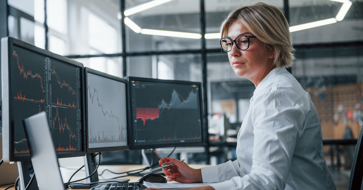 Woman analysing multiple computer screens of graphs