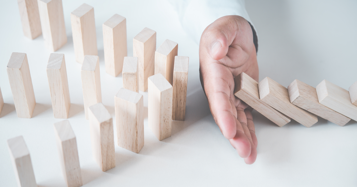 Hand stopping domino blocks from knocking down