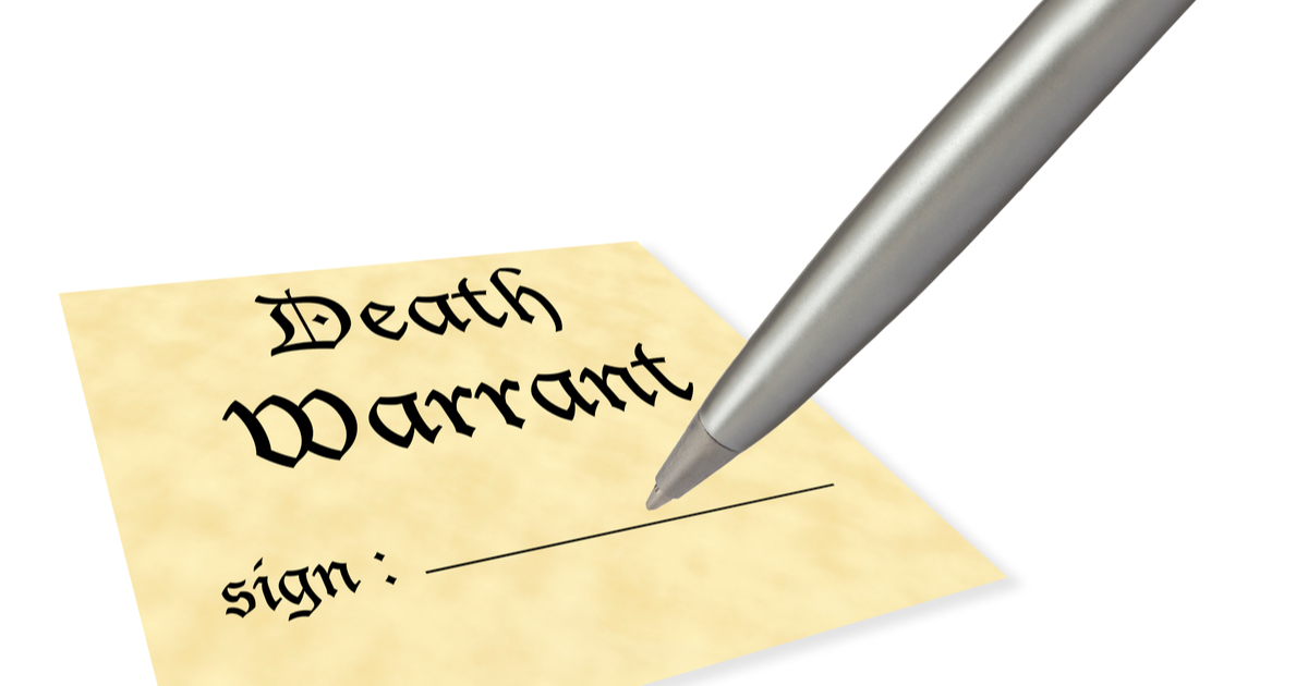 The words Death Warrant on piece of paper with a pen about to sign
