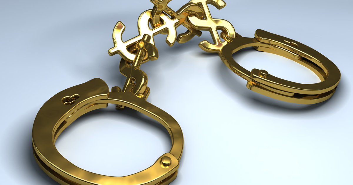 Gold handcuffs held together by dollar signs
