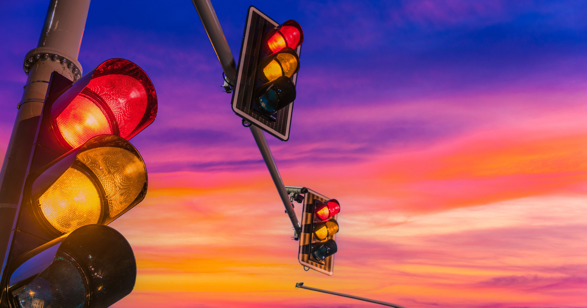 Traffic lights showing red and amber against sunset backdrop