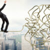Businessman balancing on tangled rope in the sky