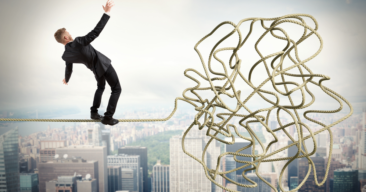 Businessman balancing on tangled rope in the sky