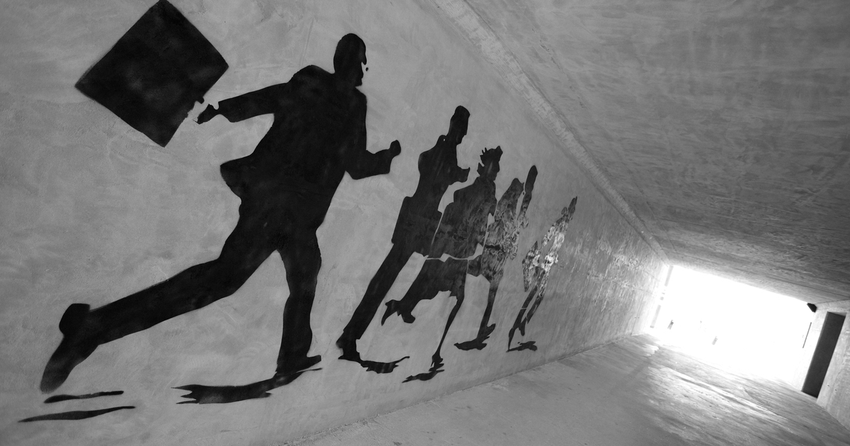 Shadows on wall of businessmen running towards white light