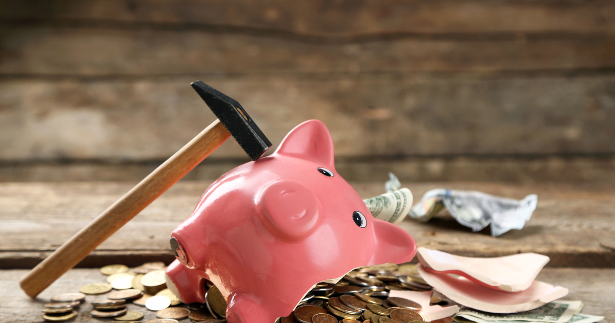 Hammer next to a broken piggy bank with fallen coins and notes