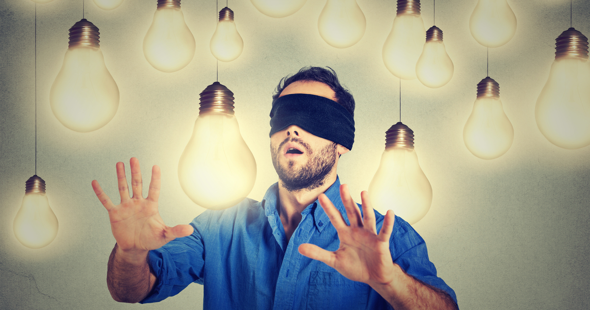 Blindfolded man feeling his way through lightbulbs