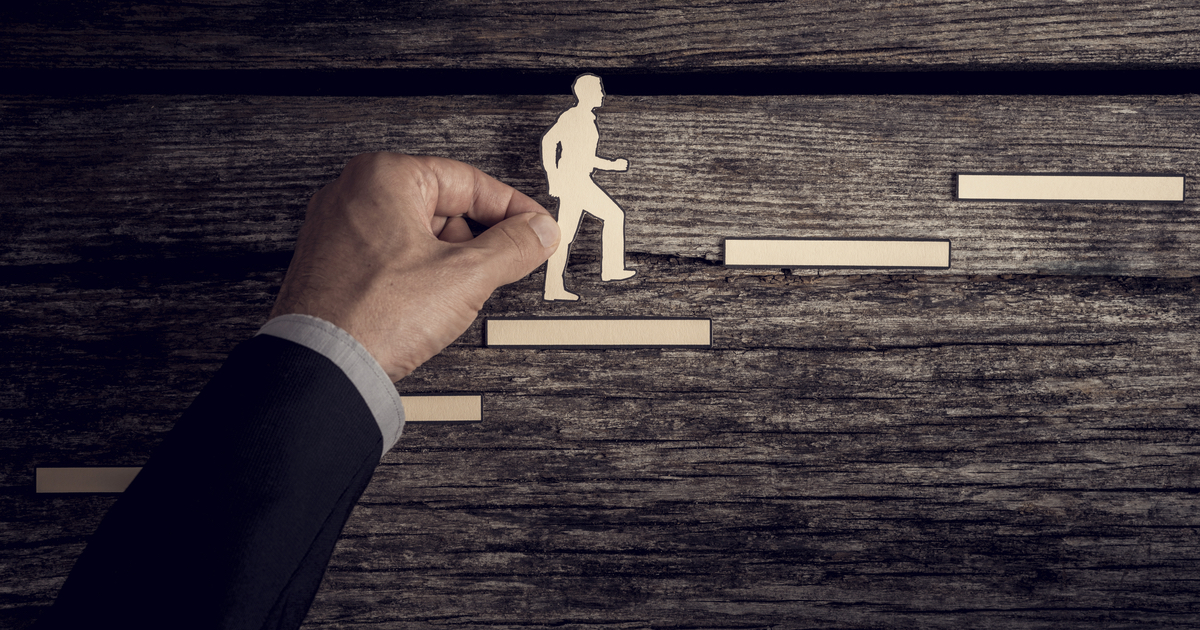 Man holding cut-out of man climbing steps