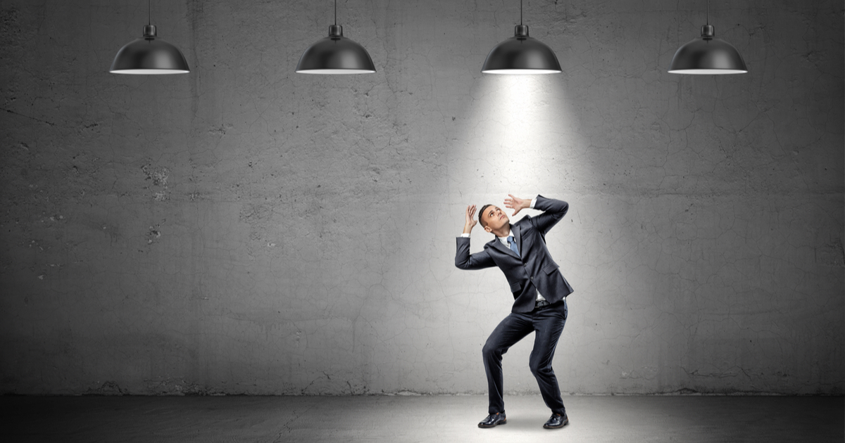 Businessman under a spotlight with three other lights off