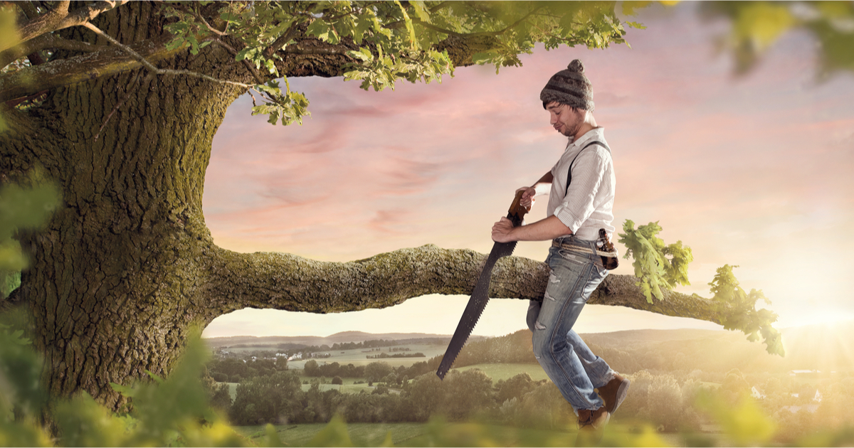 Man sitting on tree branch and sawing it off